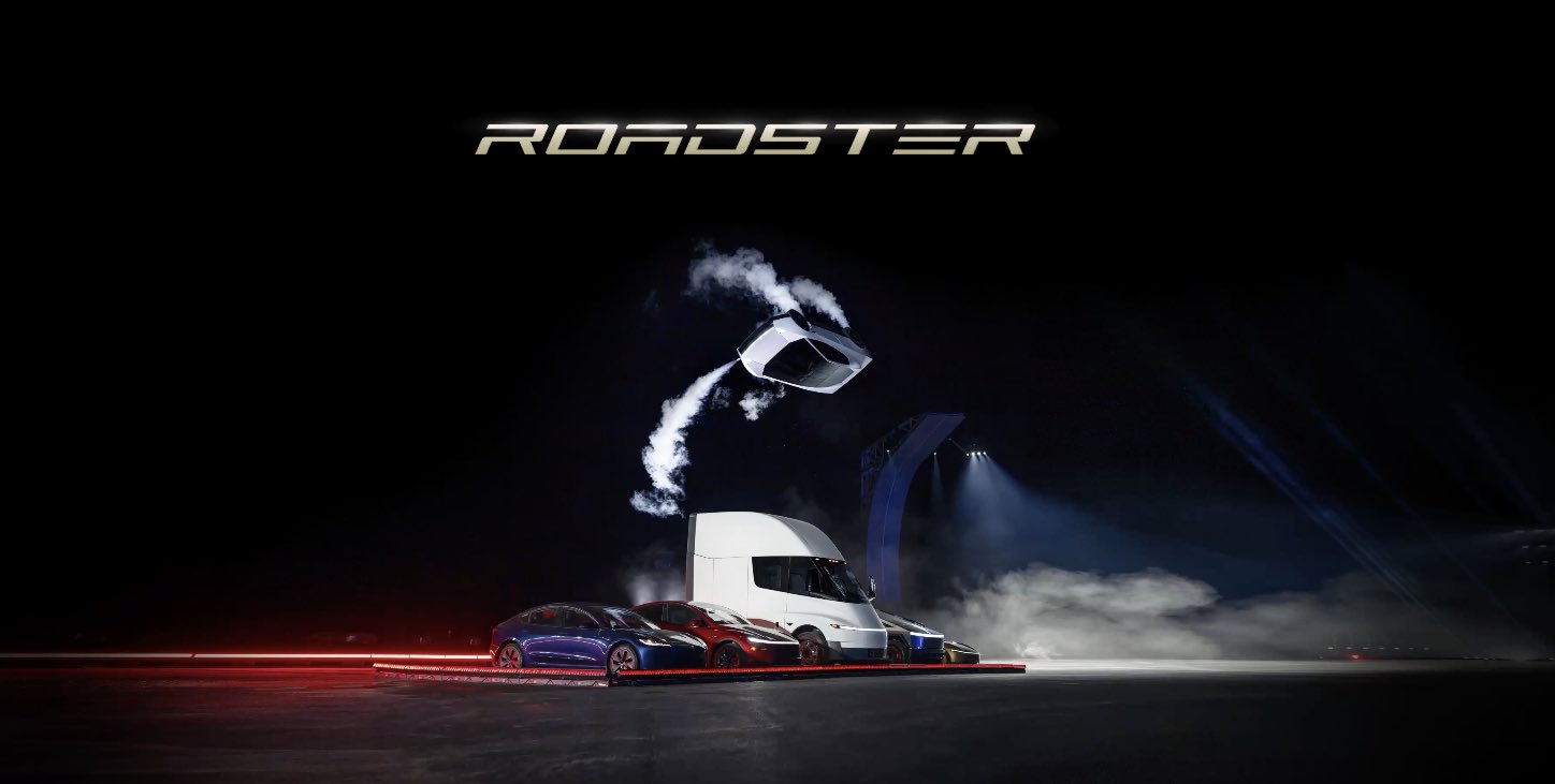 A white Tesla Roadster upside down in mid-air on thruster plumes above a row of Tesla vehicles, including a Semi, under the word ROADSTER